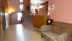 Un espace d’accueil comprenant un comptoir de réception, un canapé, un escalier et une plante en pot.
