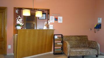 A reception area with a wooden desk, a wicker sofa, and a telephone.