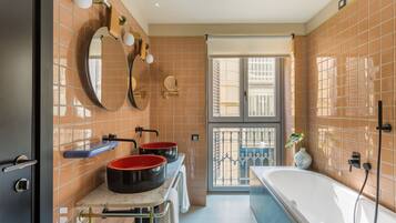 Un baño con dos lavamanos, una bañera grande y una ventana con vistas a un balcón.