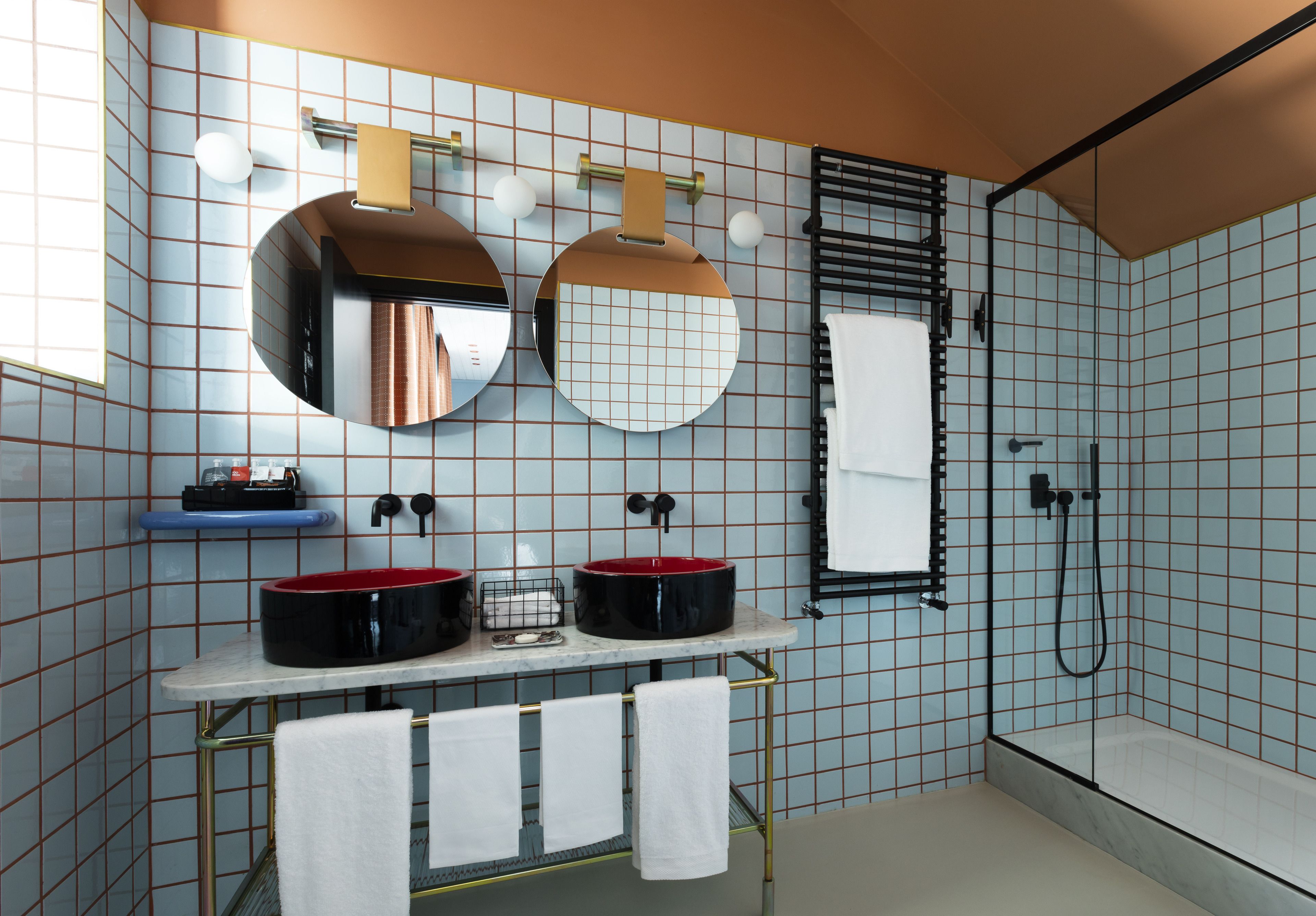 A bathroom with two sinks, a mirror, a towel rack, and a shower.