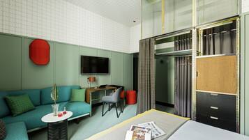 Une chambre d’hôtel moderne équipée d’un canapé, d’une petite table, d’un bureau, d’un lit, d’une armoire et d’un téléviseur.