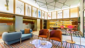 A modern lobby with a blue sofa, orange armchairs, and a glass coffee table.