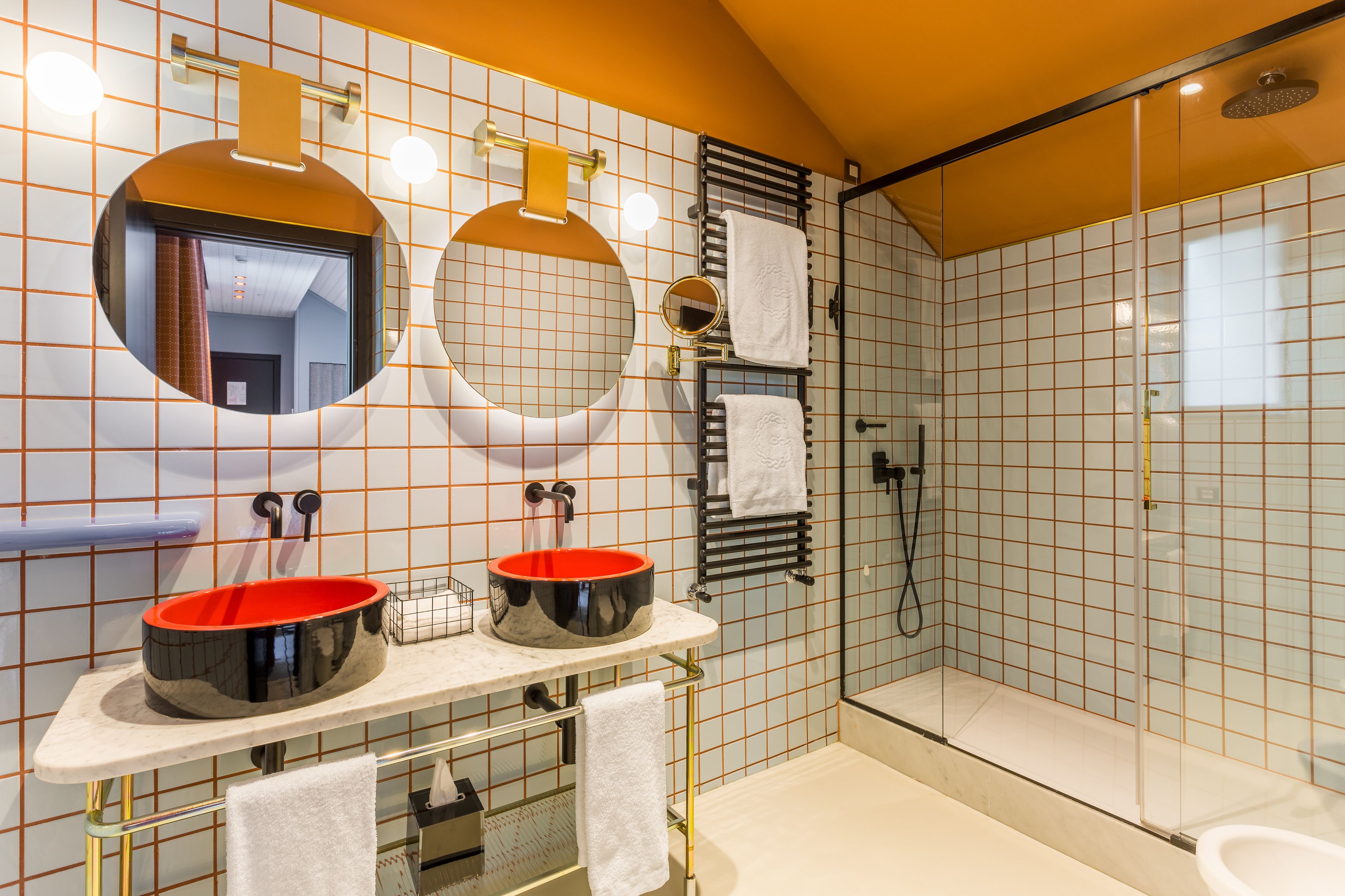 Une salle de bain moderne avec deux lavabos, un grand miroir et un espace douche.