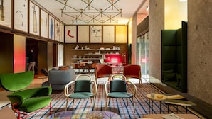A modern lobby with green and red seating, a patterned carpet, and artwork on the walls.