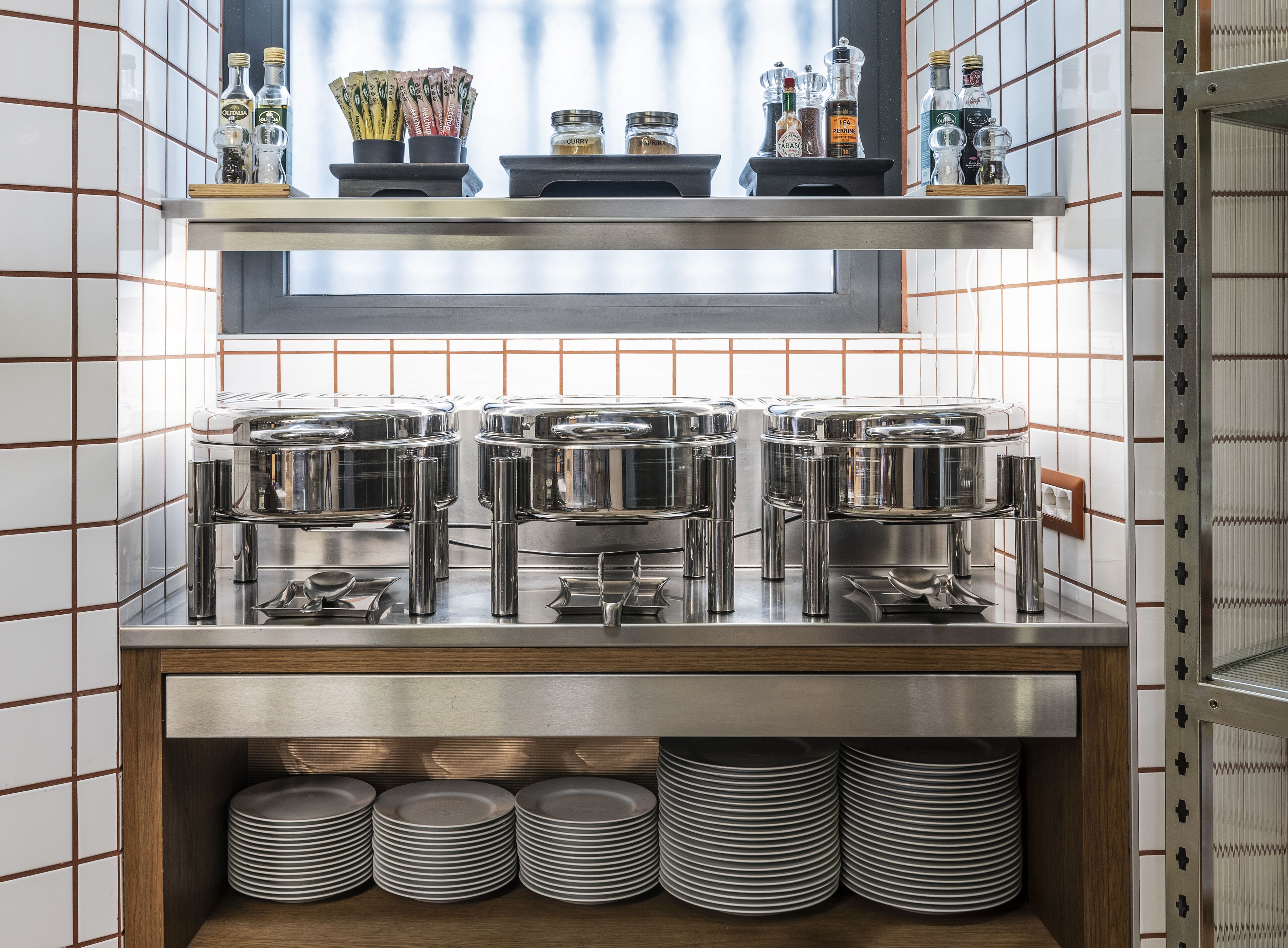 A buffet setup with multiple serving stations, condiment dispensers, and stacked plates.