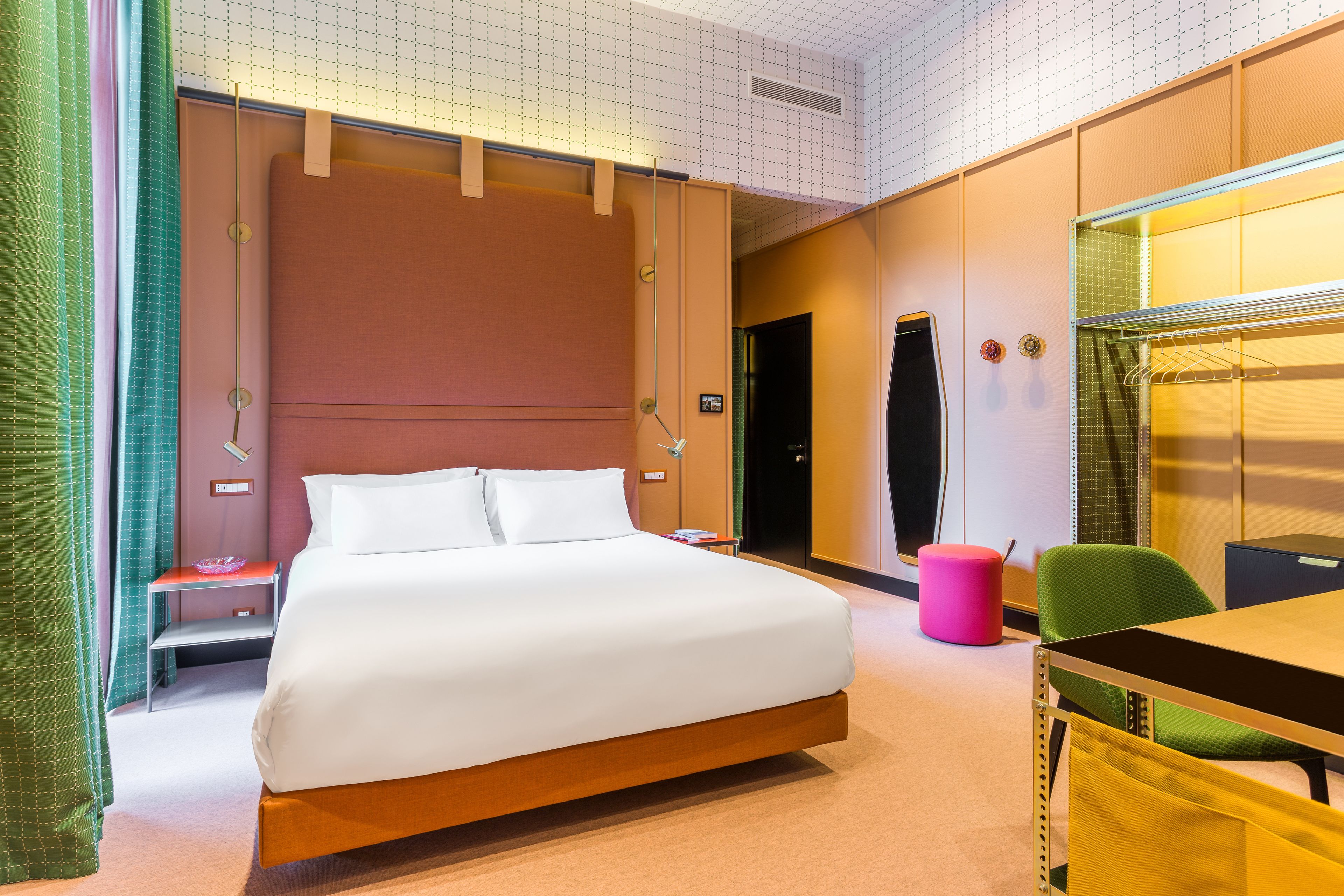 Una habitación de hotel con una cama grande, un escritorio, una silla y un espejo.