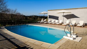 A swimming pool with lounge chairs and umbrellas, surrounded by a low stone wall. - Can Barnosell - Els Masos d'en Coll (Fontanilles)