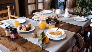 A breakfast table set with plates, croissants, orange juice, and a bottle of olive oil. - Can Barnosell - Els Masos d'en Coll (Fontanilles)