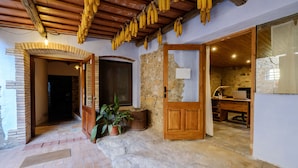 A rustic interior with exposed stone walls, a wooden door, and a desk with a lamp. - Can Barnosell - Els Masos d'en Coll (Fontanilles)