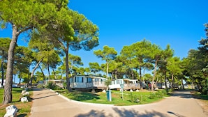 A campground with mobile homes, a paved road, and surrounding trees. - Arena Indije Mobile Homes (Medulin)