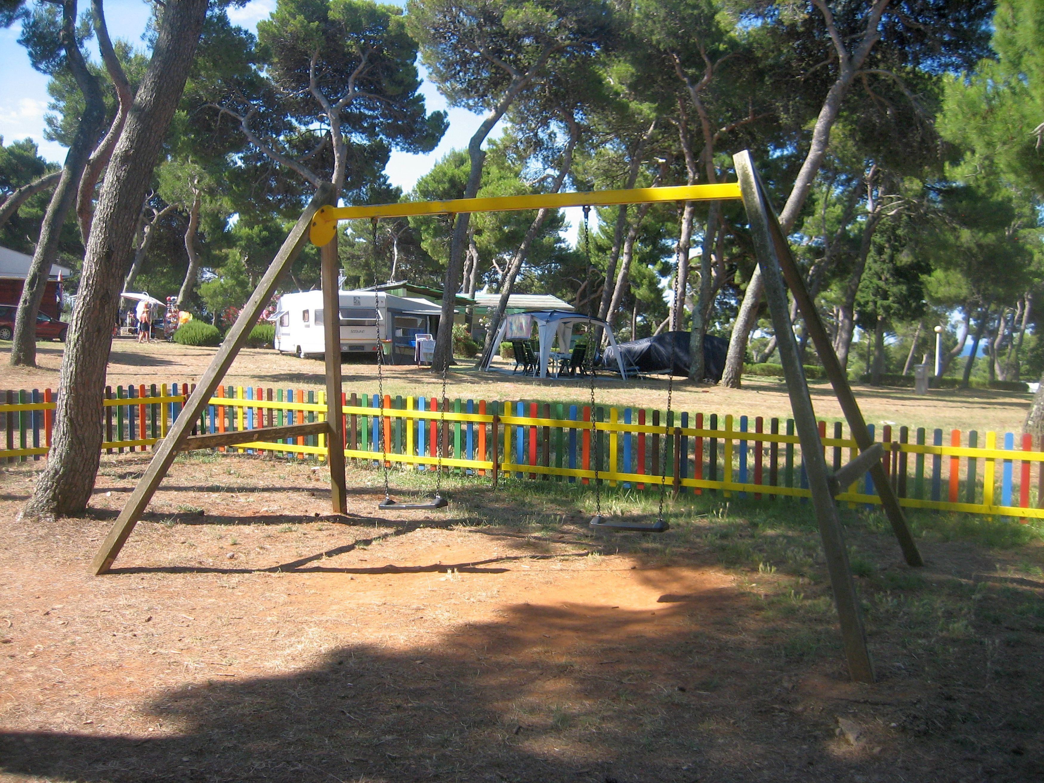 A playground with a swing set and a colorful fence.