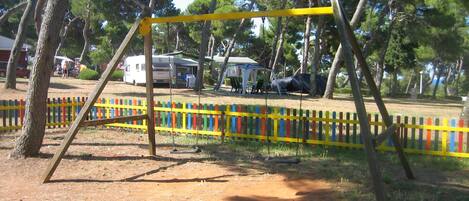 A playground with a swing set and a colorful fence.