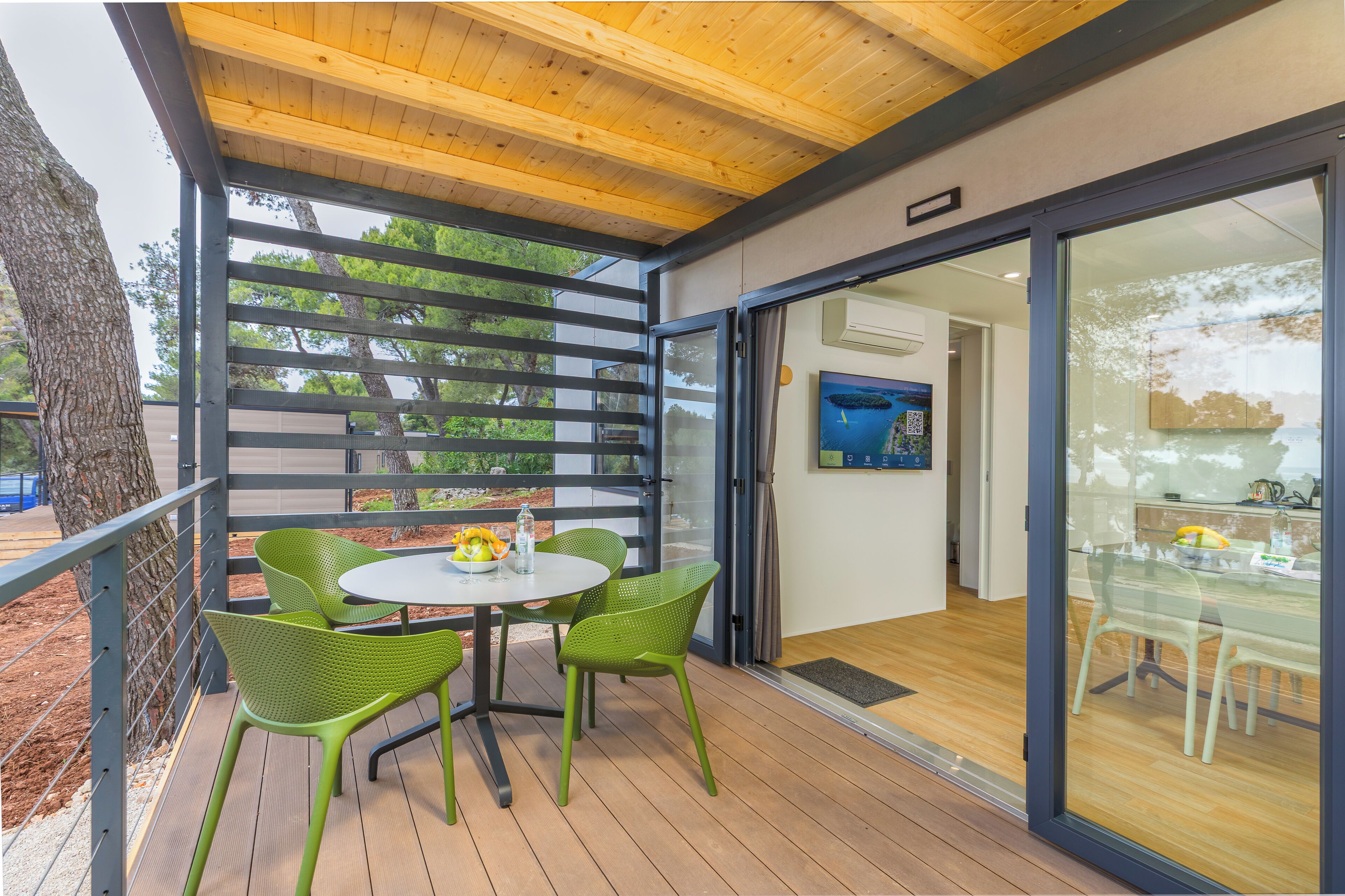 Un área de estar al aire libre techada, con una mesa y sillas, techo de madera y vistas al exterior.