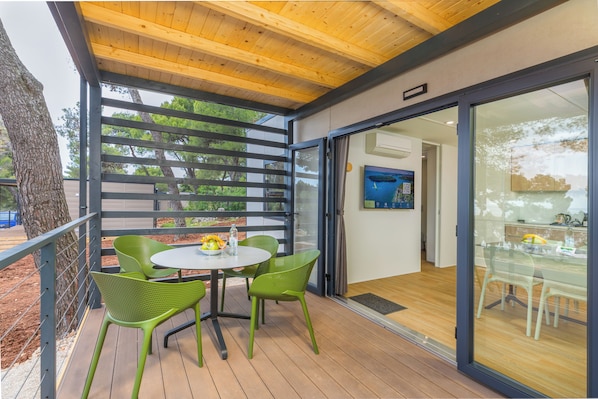 A covered outdoor seating area with a table and chairs, a wooden ceiling, and a view of the outdoors.