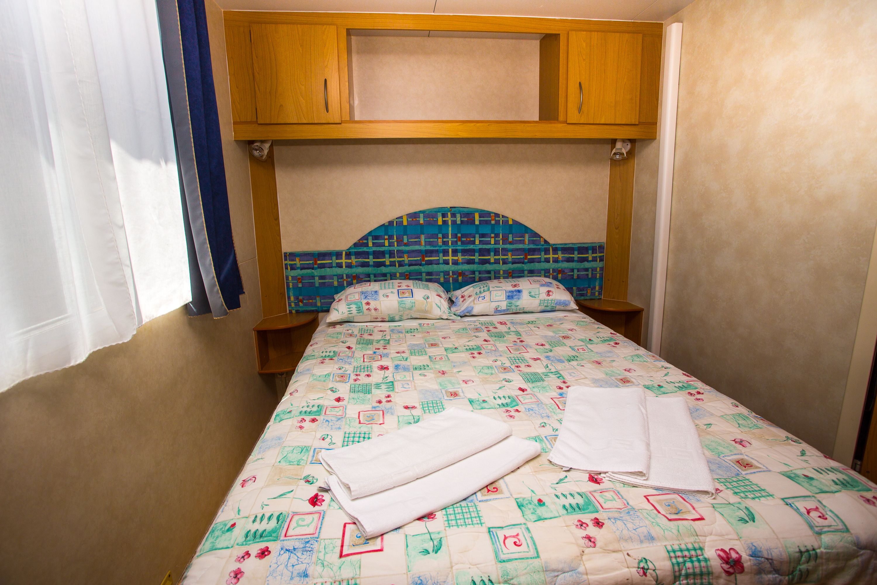 Ein Schlafzimmer mit einem Bett, einem Holzkopfstück und einer gesteppten Bettdecke.