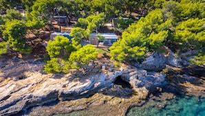 A coastal property with a rocky shoreline, clear water, and lush greenery. - Arena Stoja Camping Homes (Pula)