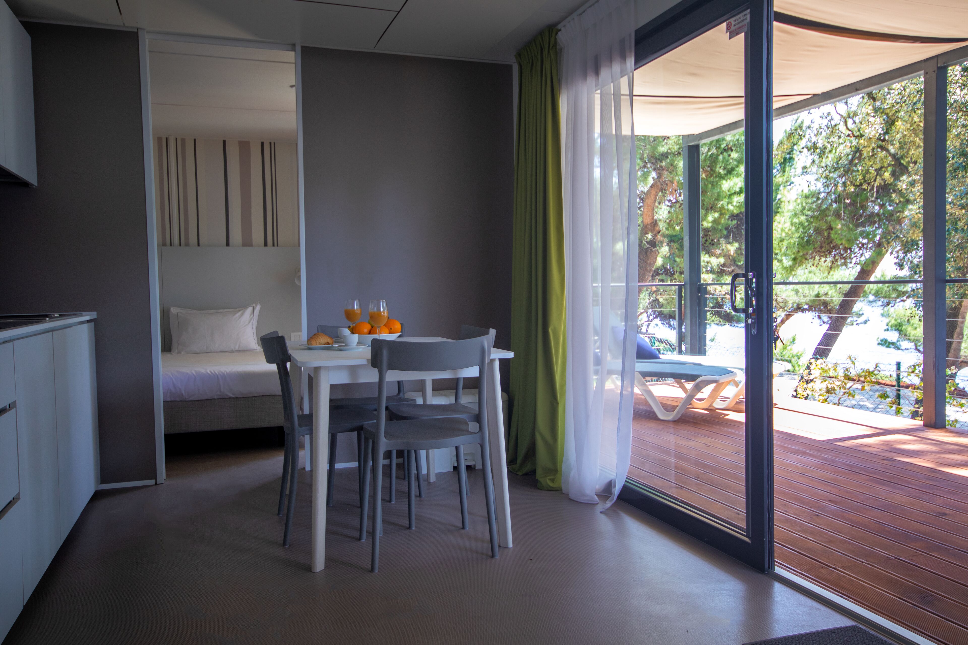 Una habitación compacta con cama, una mesa de comedor con sillas y vistas a una terraza exterior.