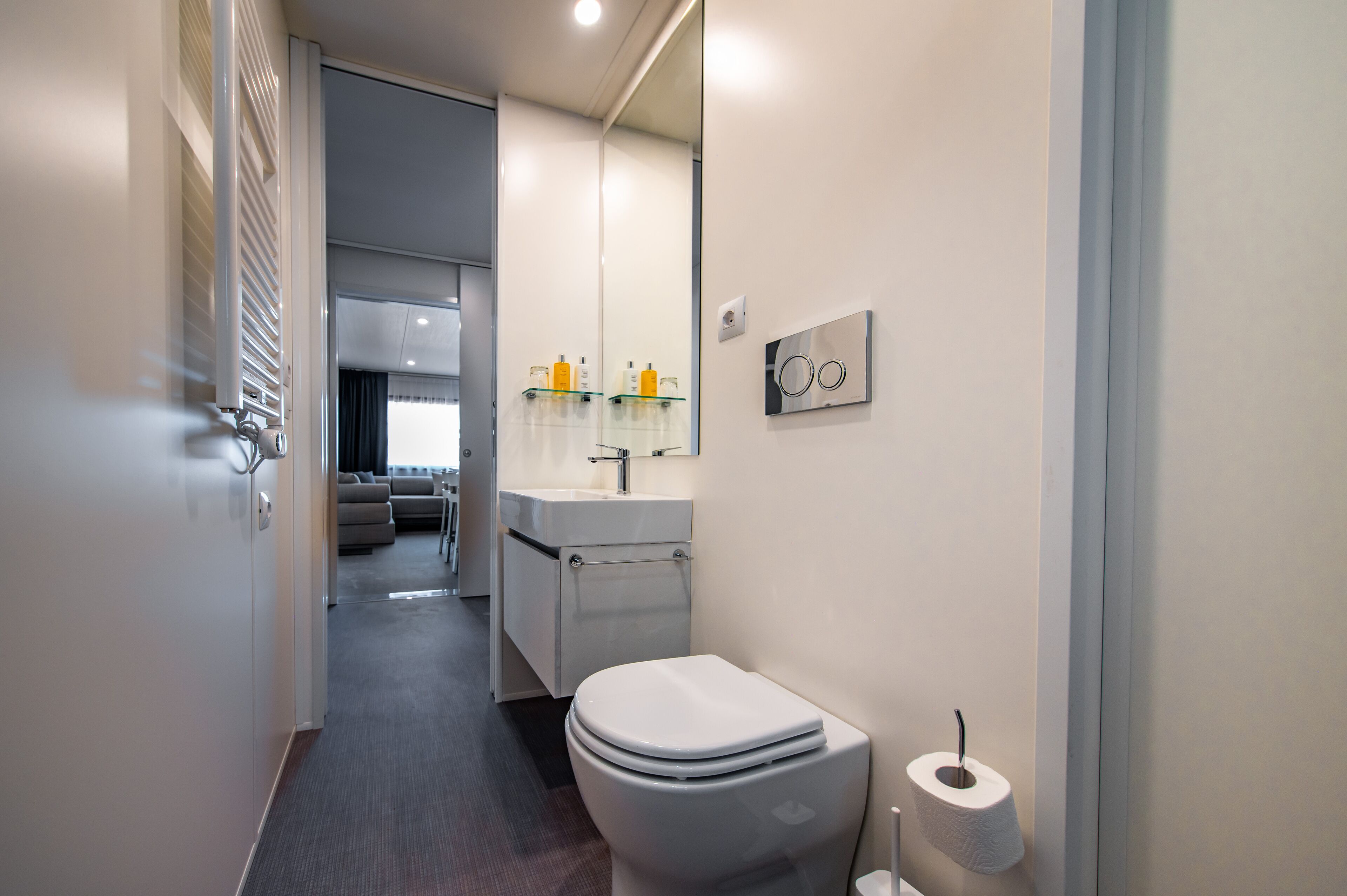 Ein modernes Badezimmer mit Toilette, Waschbecken und Spiegel.