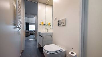 Ein modernes Badezimmer mit Toilette, Waschbecken und Spiegel.