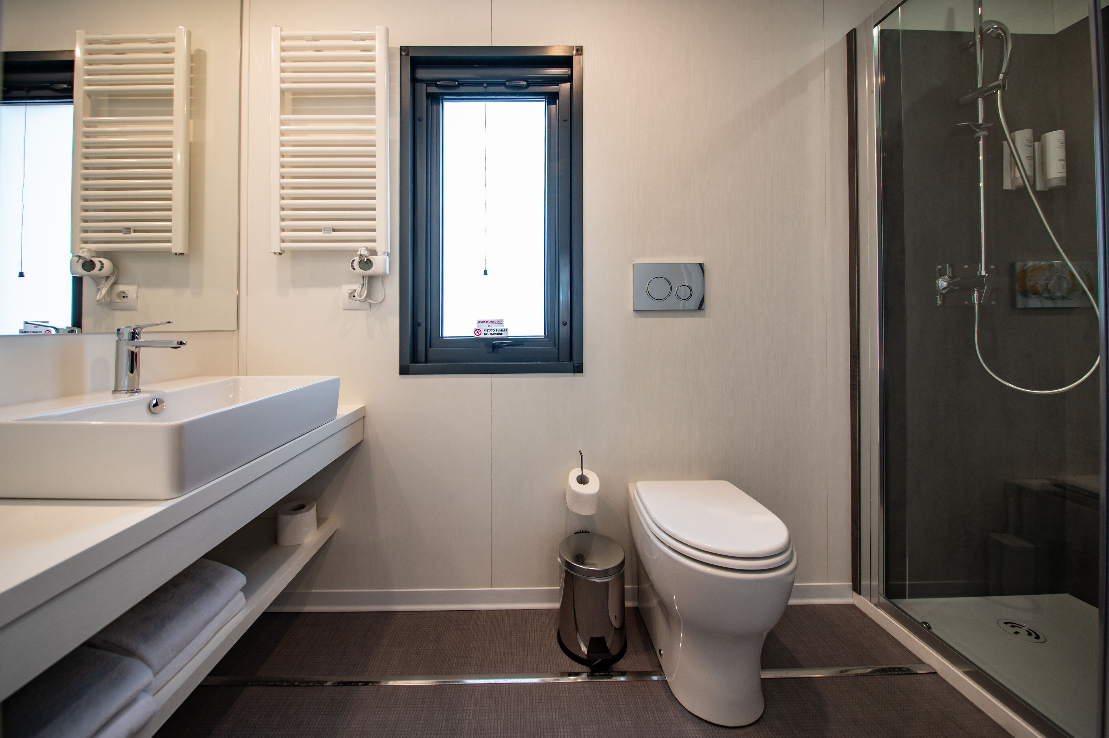 A modern bathroom with a white sink, toilet, and glass shower enclosure.