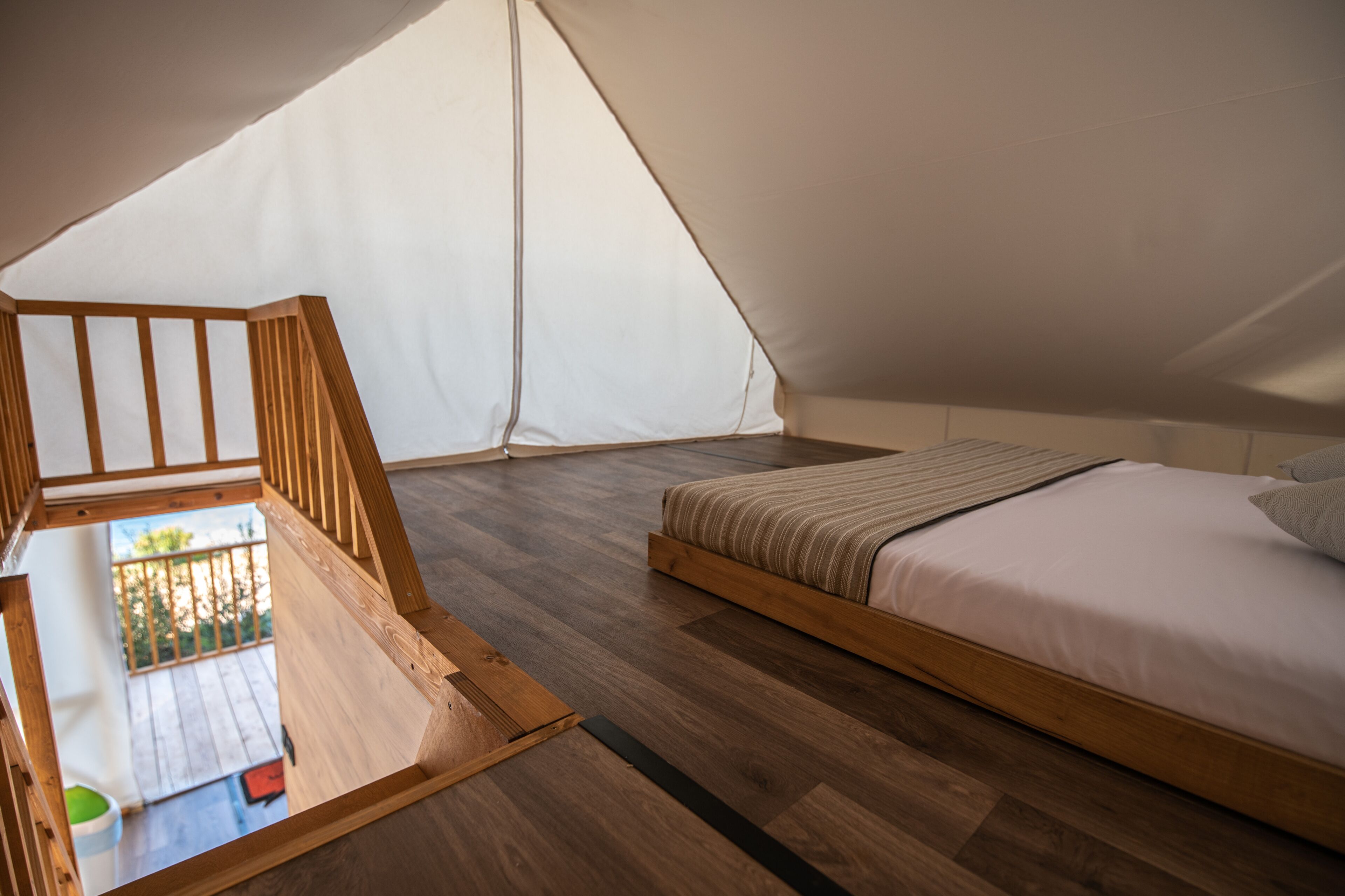 Una habitación con toldo, una cama de madera y una pequeña mesa de madera.
