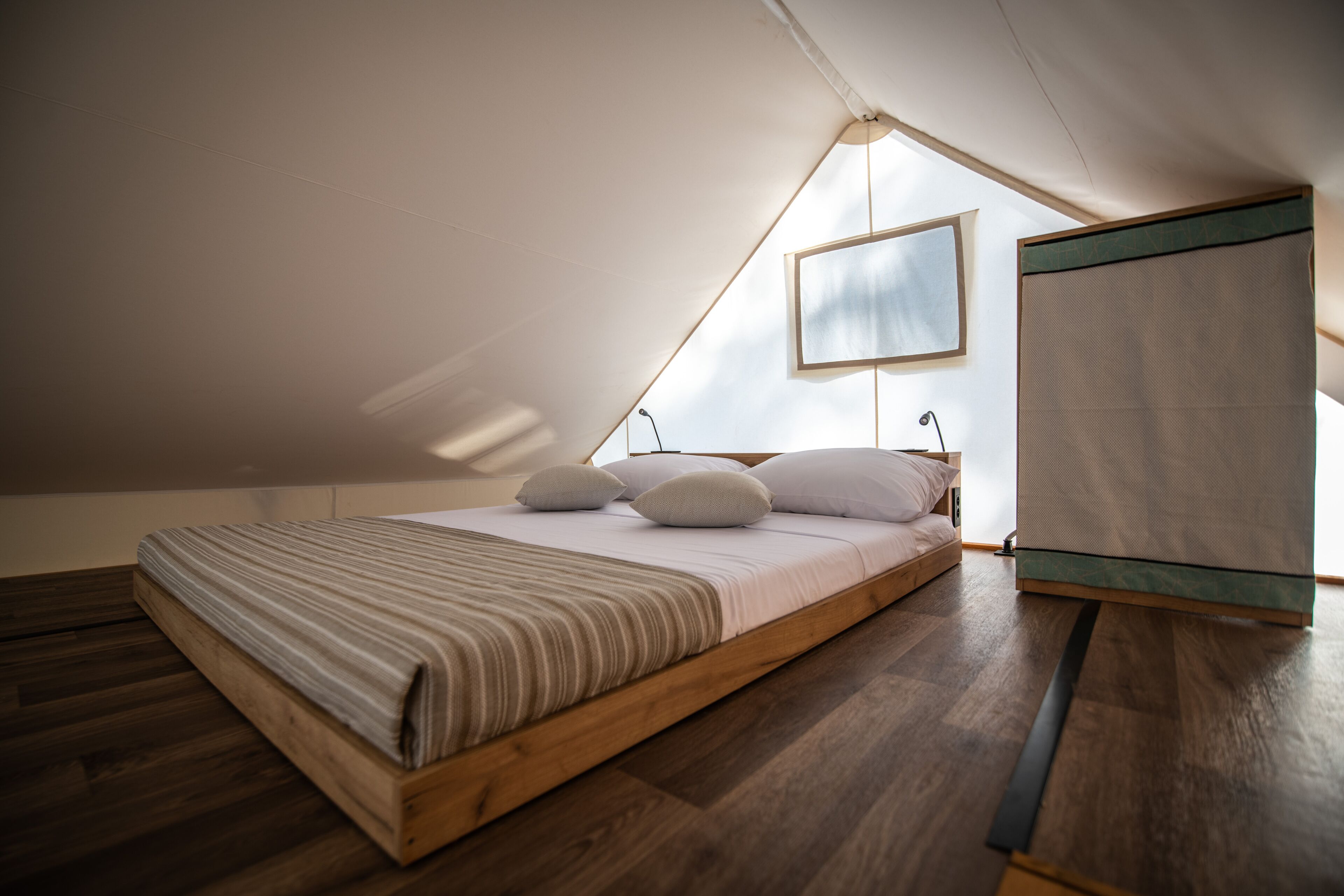 Ein Schlafzimmer mit einem hölzernen Bett, einem Fenster und Blick zum Himmel.