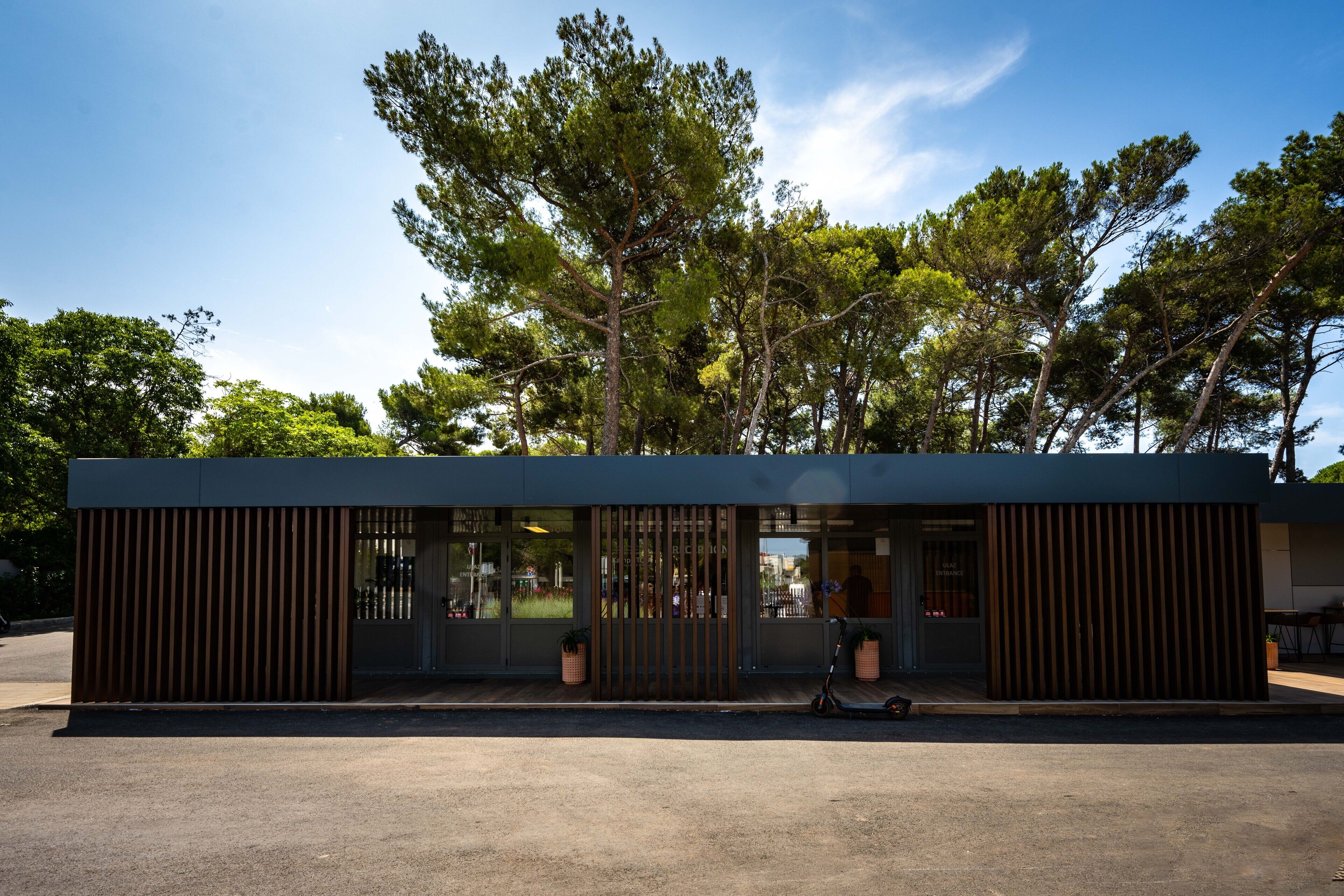 Un bâtiment moderne doté d’un toit plat, de grandes fenêtres et d’une façade en bois.