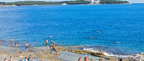 A beach with people sunbathing and swimming.