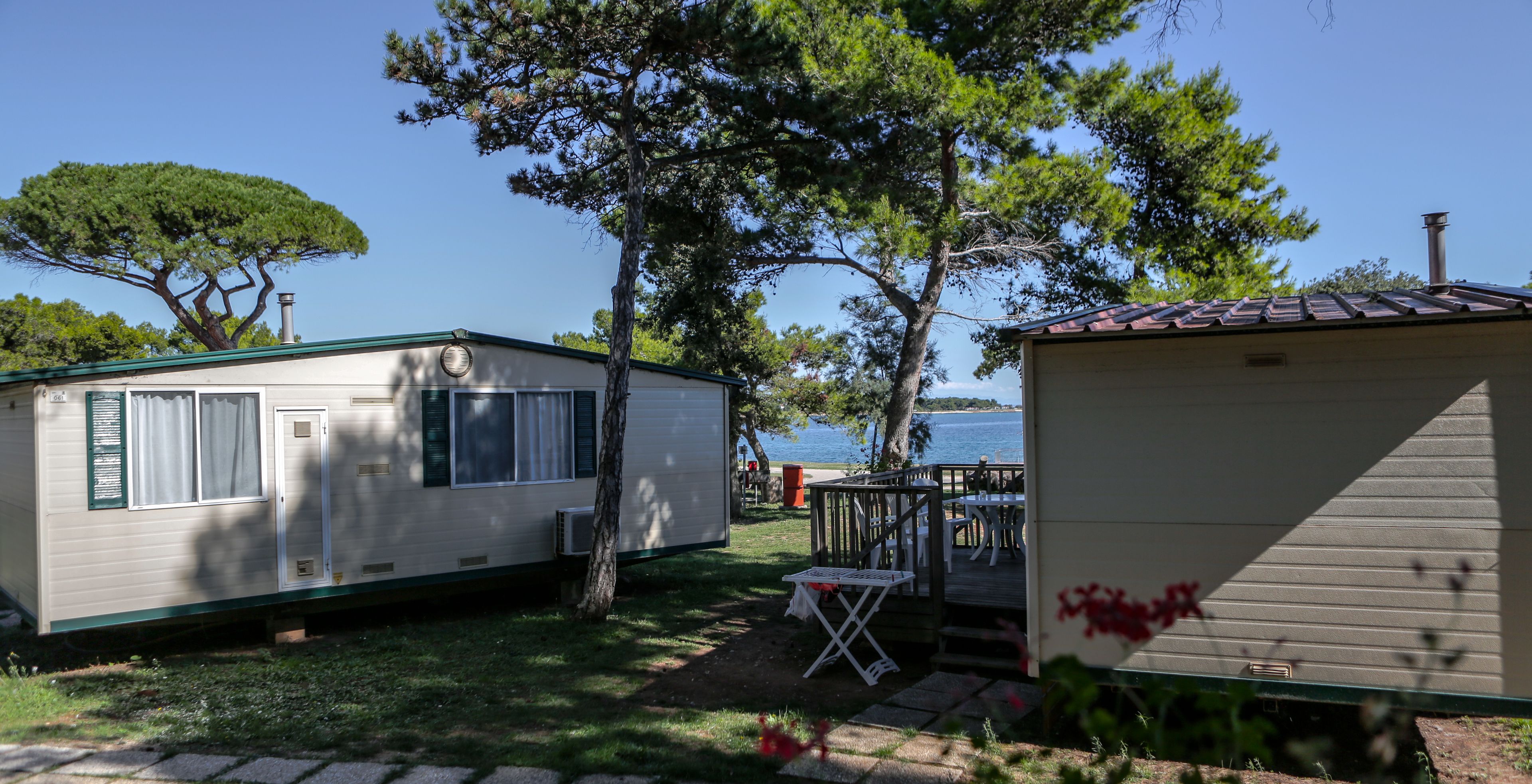 A mobile home with a small deck and a covered outdoor seating area.