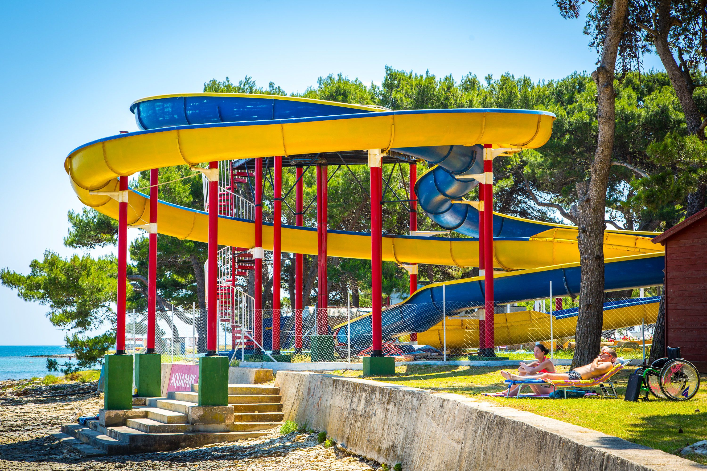 Un parc aquatique doté de nombreux toboggans et d’une zone de plage avec des chaises longues.