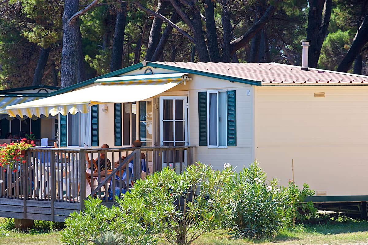 A single-story mobile home with a porch and a covered outdoor seating area.