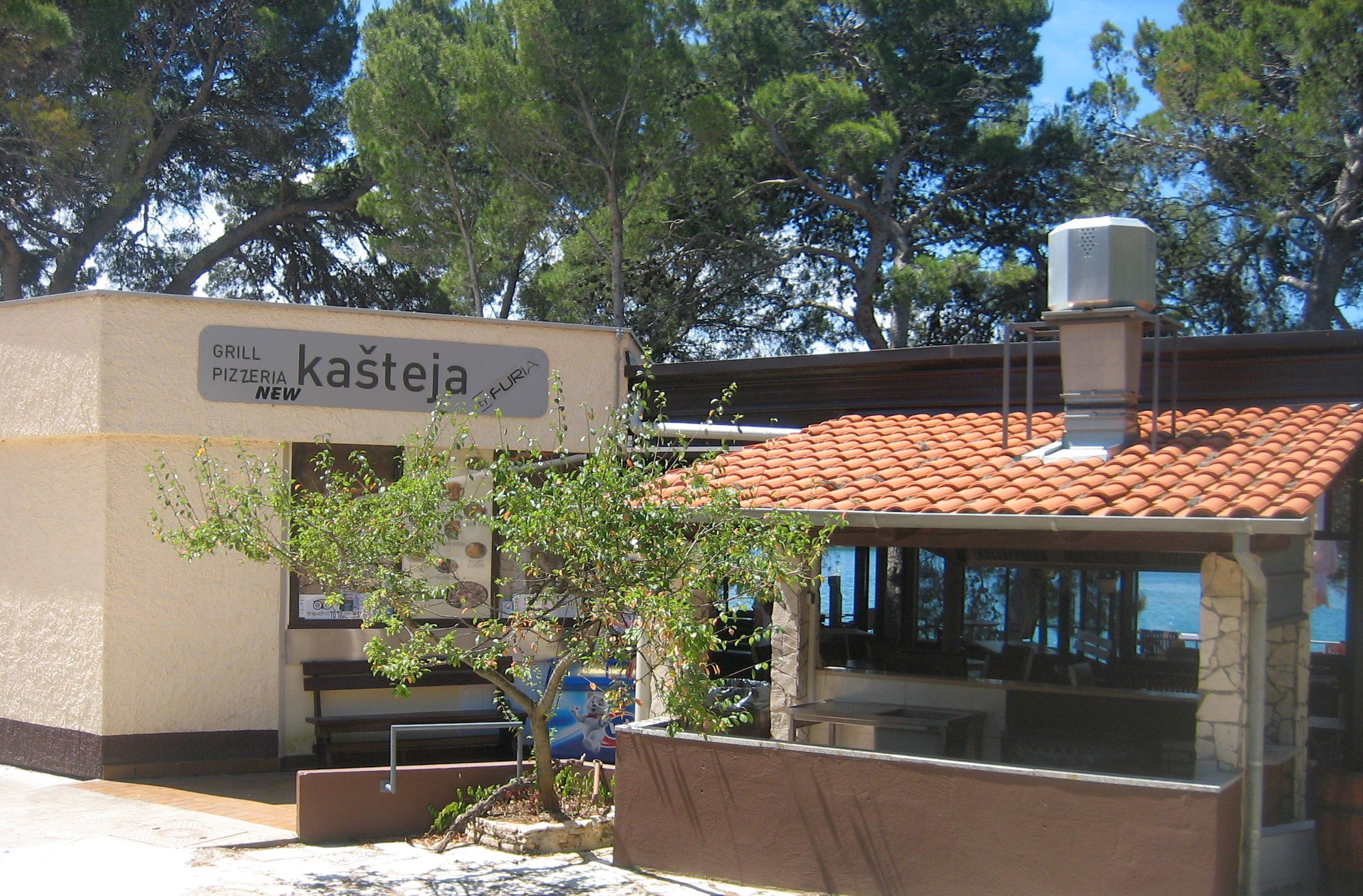 A building with a sign for a new grill and pizzeria.
