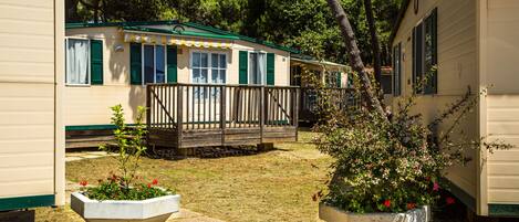 A row of mobile homes with a wooden deck and potted plants.