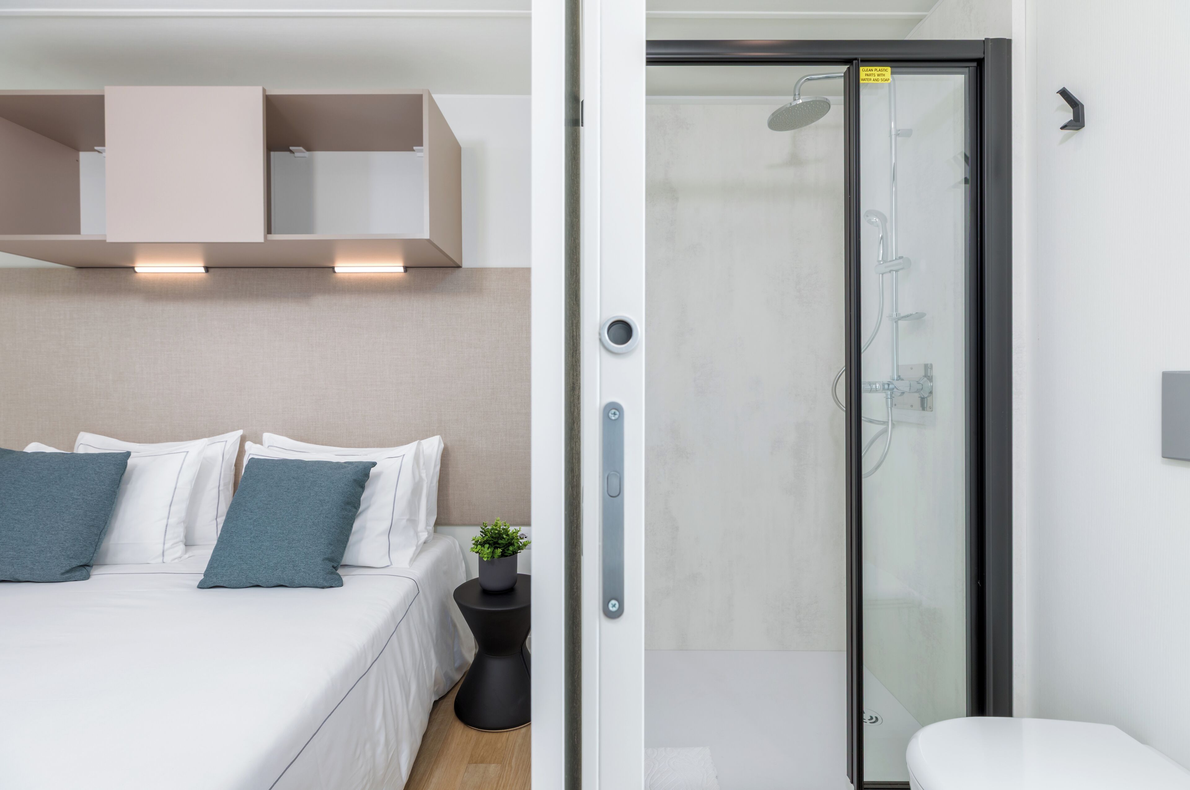 Una camera d'albergo moderna con un letto, un comodino e uno spazio doccia.