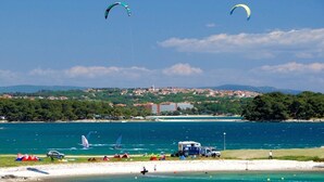 A coastal area with a beach, tents, and a few sailboats. - Arena Stupice Camping Homes (Medulin)