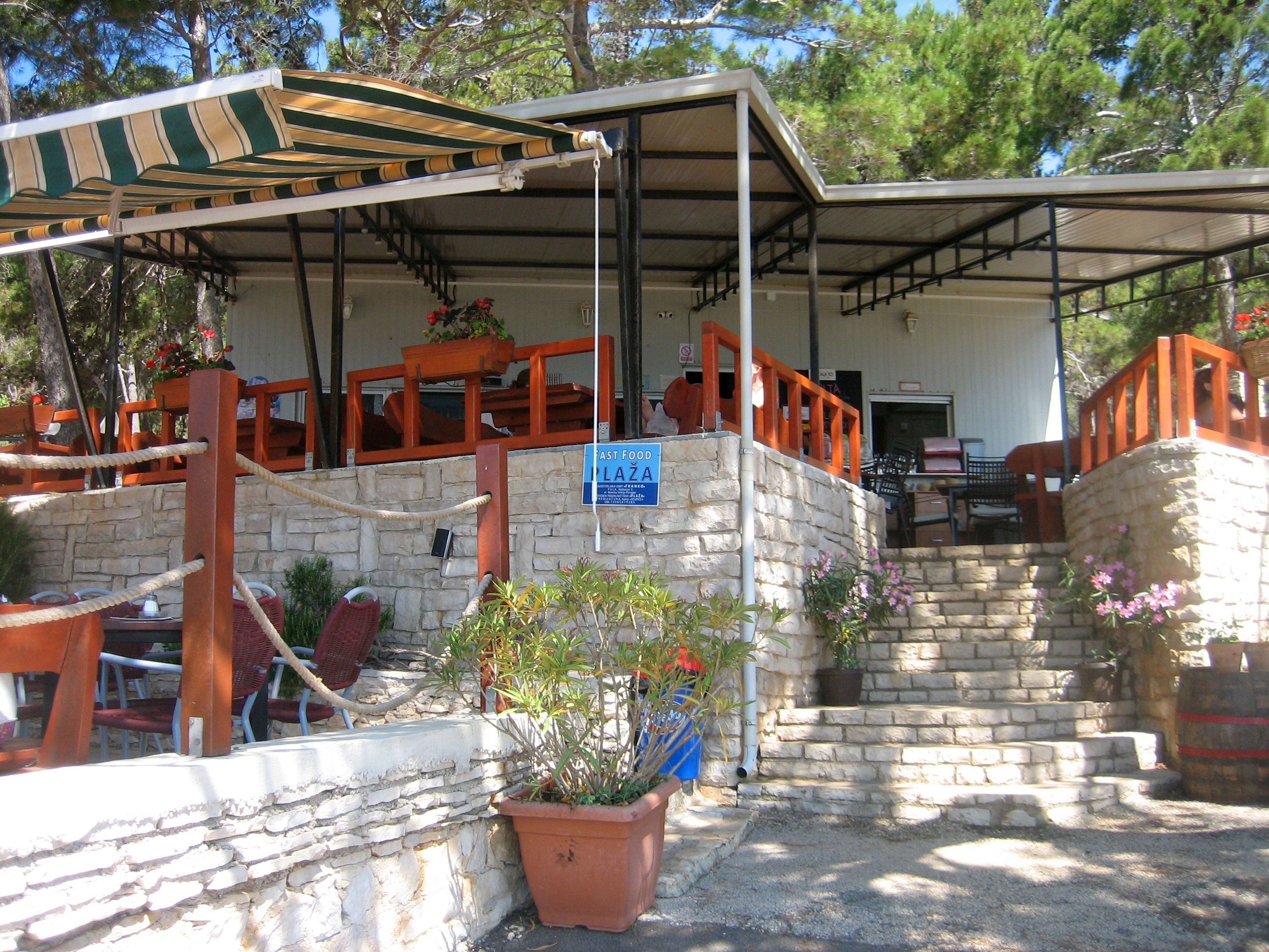 A covered outdoor seating area with stone walls and potted plants.