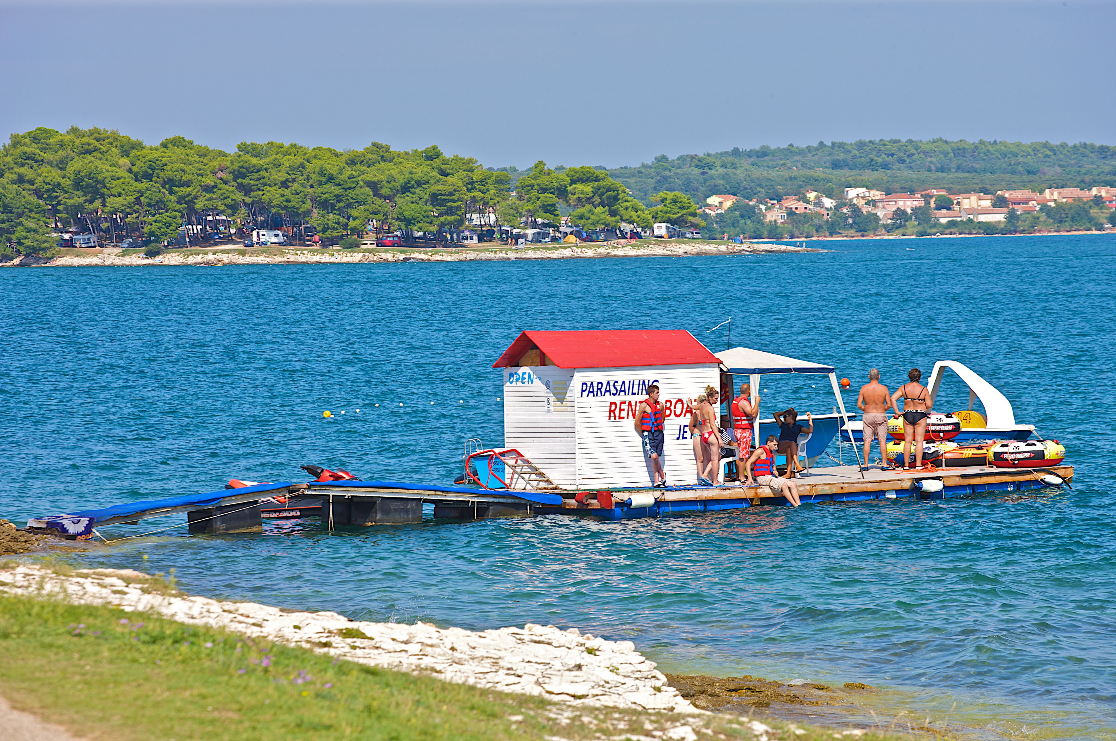 A parasailing boat with a red canopy and a sign that reads "Parasailing Rent a Boat".
