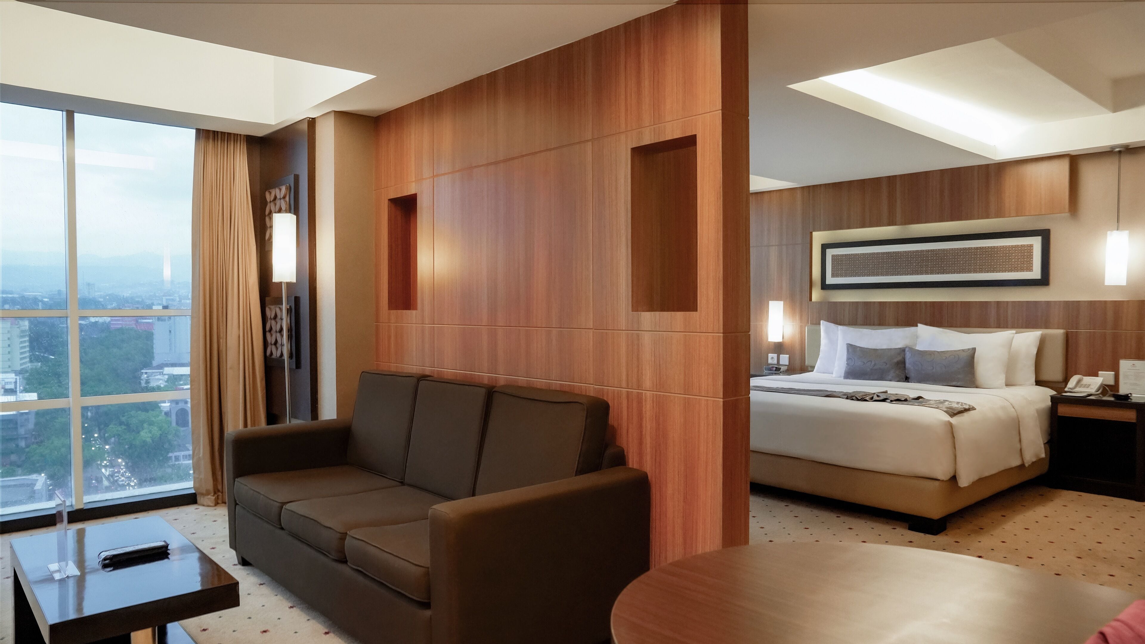 Une chambre d’hôtel avec une grande fenêtre, un canapé, un lit et une petite table.