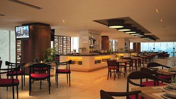 A modern restaurant with a central bar, multiple dining tables, and chairs.