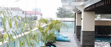 Una terraza en la azotea con asientos acolchados azules, plantas en macetas y una piscina.