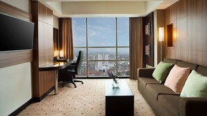 Een moderne hotelkamer met een groot raam, een bureau, een bank en een flatscreen-tv.