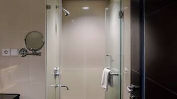 A modern bathroom with a glass-enclosed shower, a round mirror, and a towel rack.