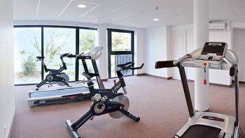 Ein Heim-Fitnessraum mit Laufband, Ergometer und Crosstrainer.