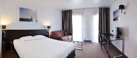 Una habitación de hotel con una cama grande, un escritorio con una silla, un sofá y un televisor.
