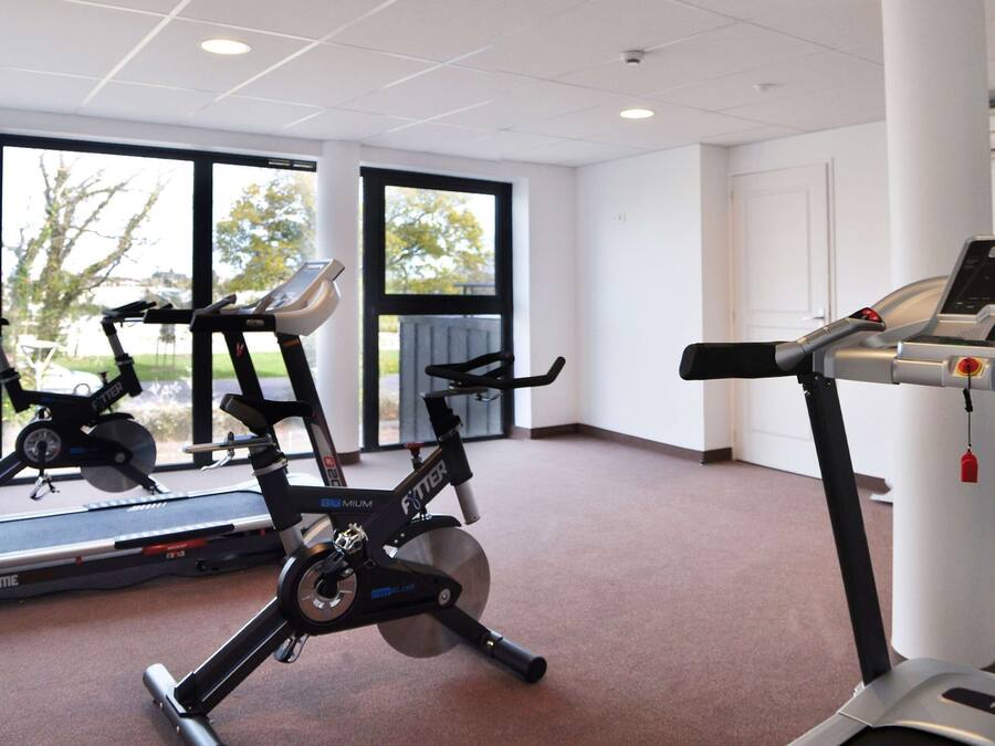 Un gimnasio con cintas de correr, bicicletas estáticas y una máquina de remo.
