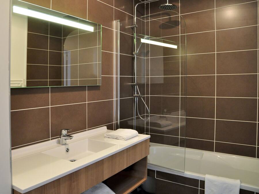 Un baño moderno con ducha envuelta en vidrio, un lavabo blanco y un espejo grande.