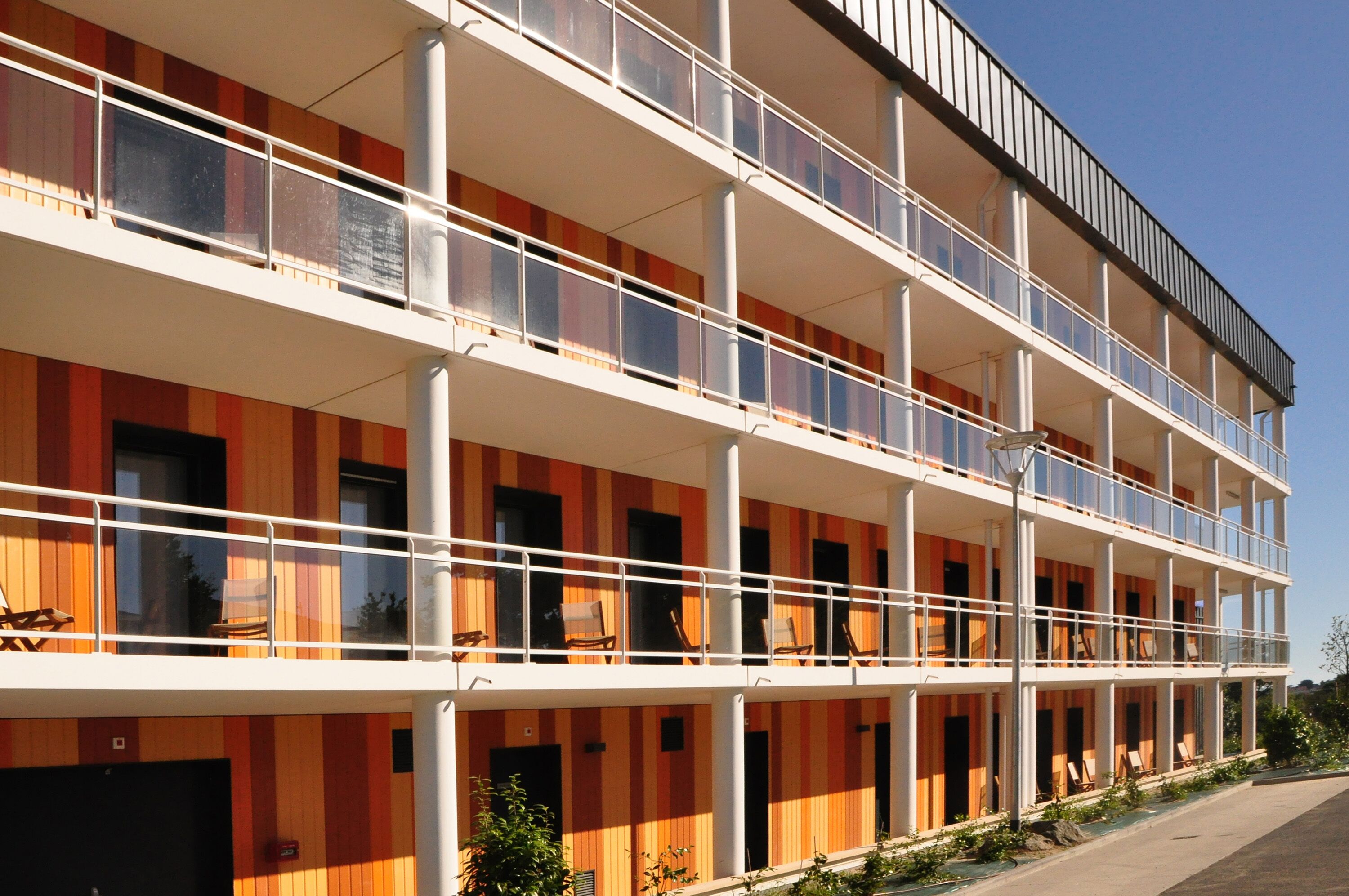 A multi-story hotel with balconies, a flat roof, and a modern design.