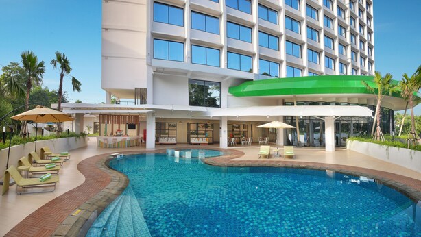 Un hotel moderno con piscina, mobiliario exterior y zona de bar.