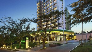 Un hotel moderno con un llamativo letrero de 'ibis Styles', un acceso ajardinado y una fachada bien iluminada.