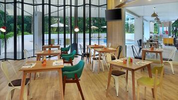 Enjoy meals in a stylish dining area with tables and chairs, surrounded by lush greenery.